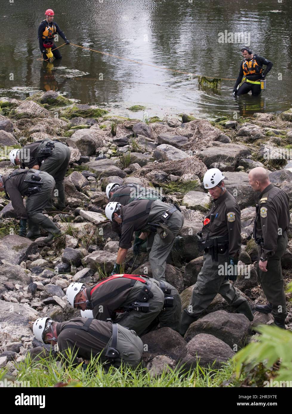 Police officers scour the banks of the MileIles River near Terrebonne