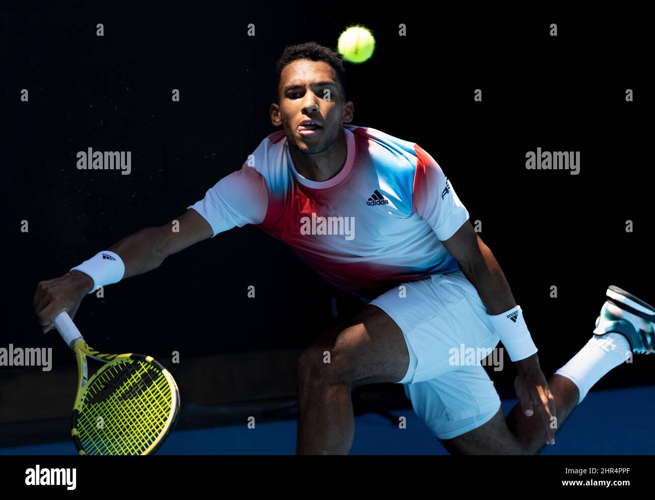 Closeup of Felix Auger Aliassime, hitting a forehand out of the shadows ...