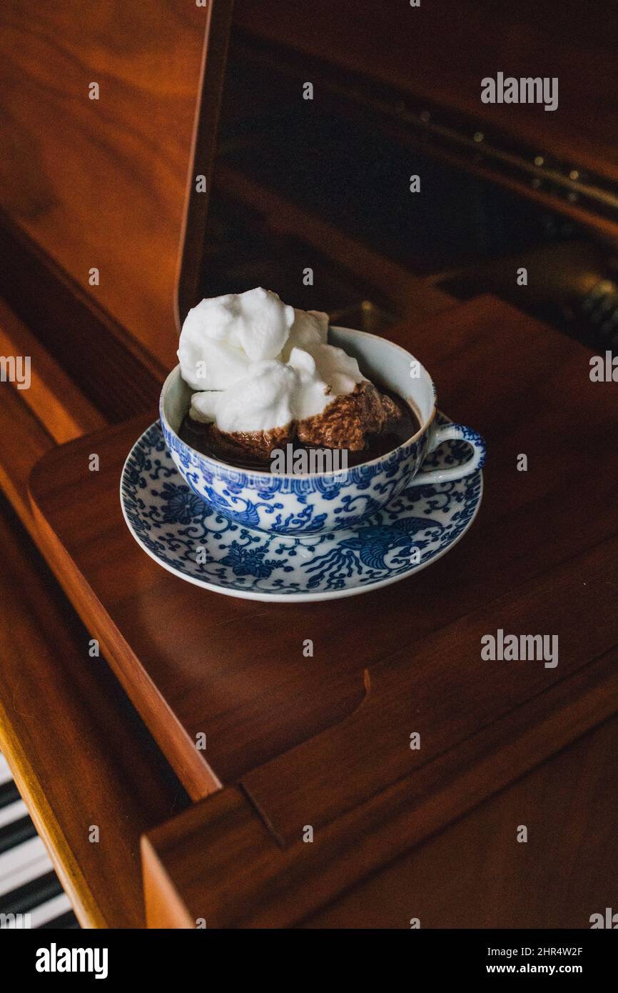 Hot drinking chocolate in blue floral teacup set with white meringue  sitting on baby grand piano Stock Photo - Alamy