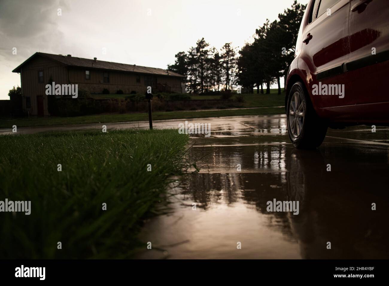Closeup of a car parked on a driveway during the rain in the daytime in