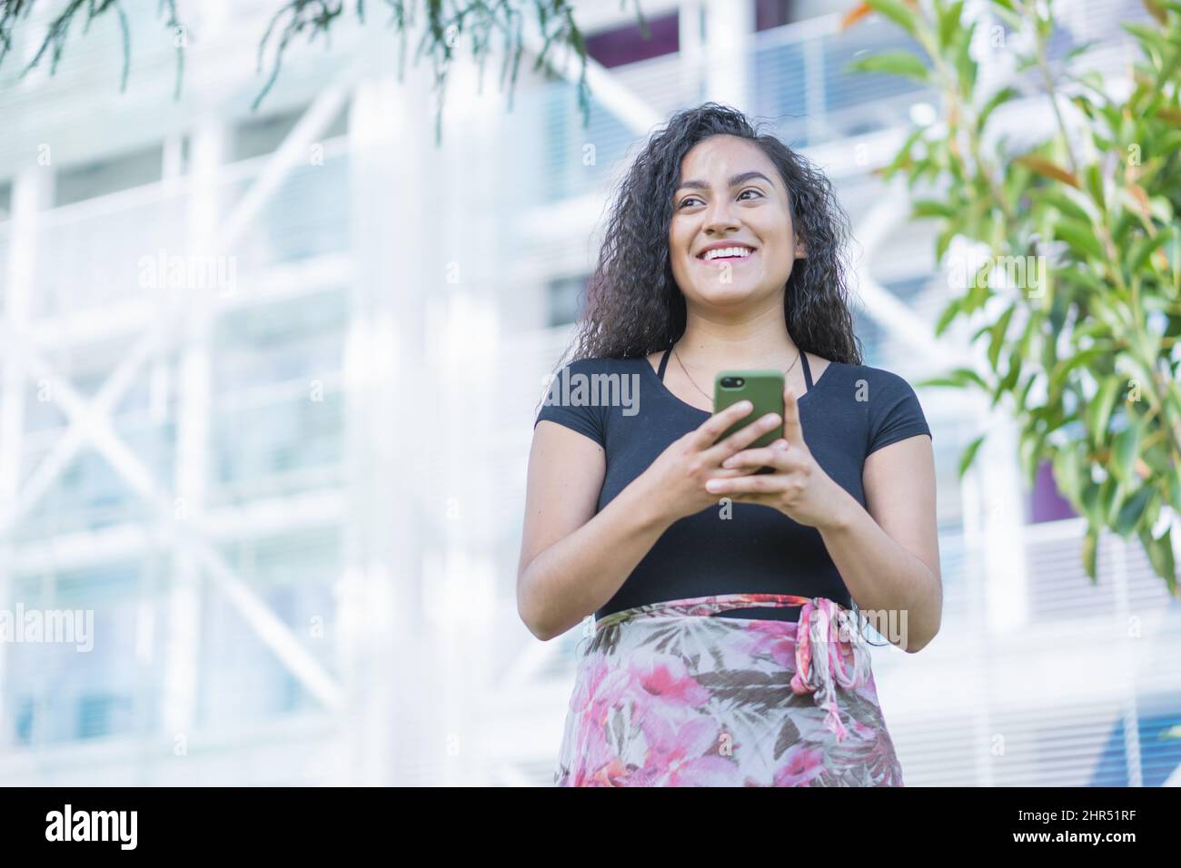 Happy Hispanic young female holding her phone Stock Photo - Alamy