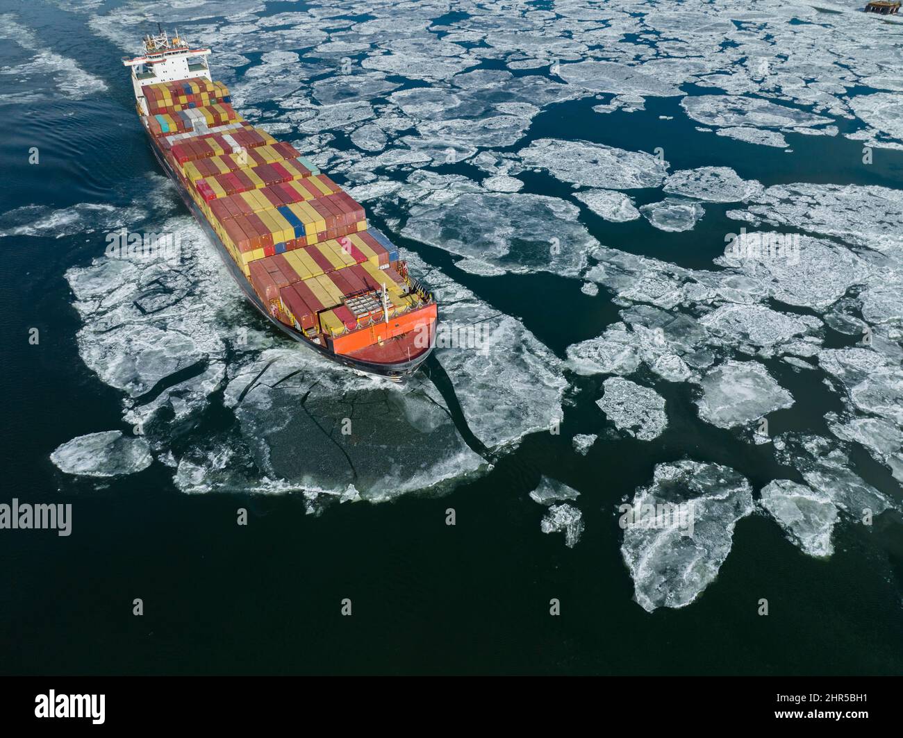 Aerial view of a container ship going upstream through winter ice in the St. Lawrence River near the port of Montreal in Canada Stock Photo