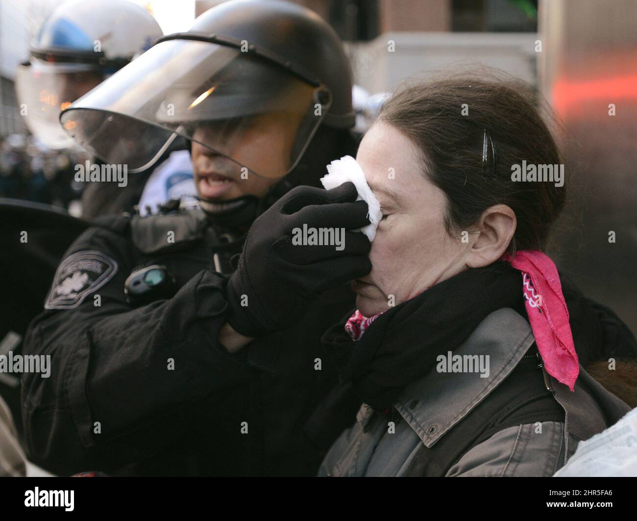 A riot police officer helps an injured woman during an anti-police brutality demonstration in Montreal on Friday March 15, 2013. Police used horses, pepper-spray and kettling tactics to clamp down Friday on an annual protest that has a history of getting rowdy.THE CANADIAN PRESS/Ryan Remiorz Stock Photo