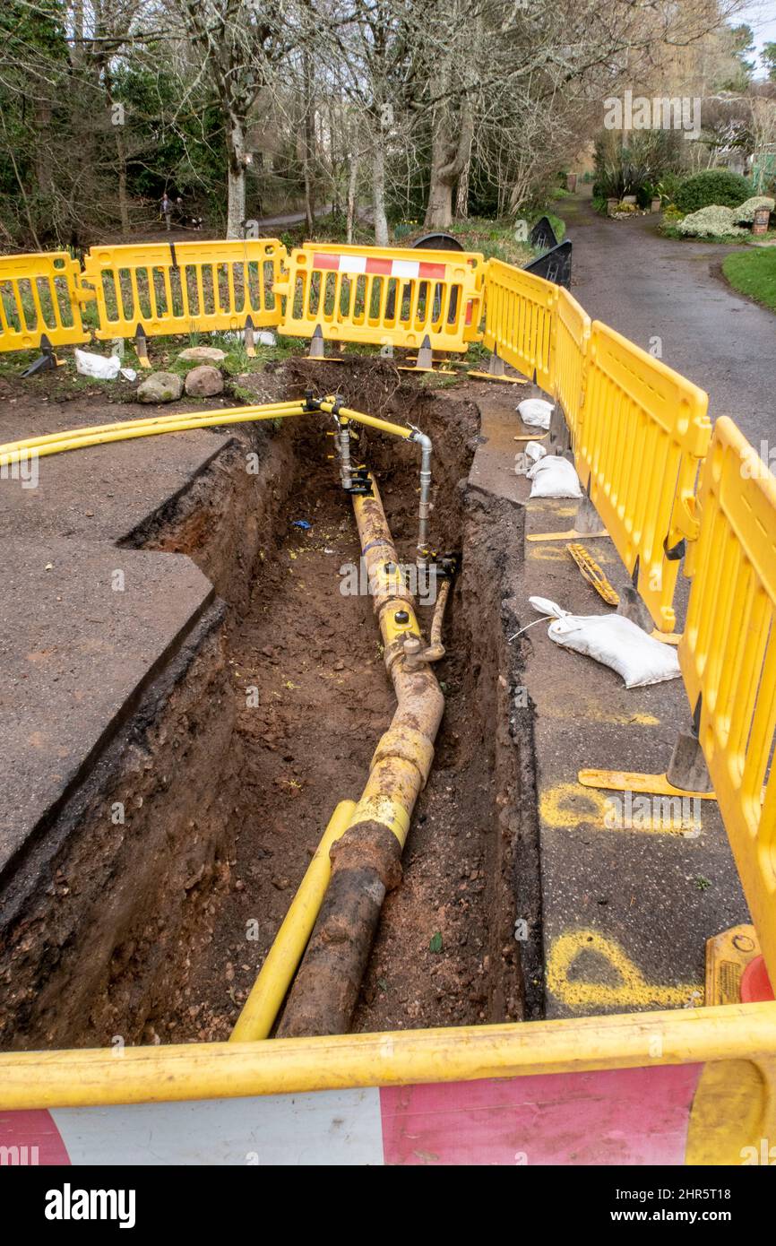 Gas main pipe uncovered during pipework replacement in Sidmouth, Devon, UK. Roadworks, hole in the ground, gas main. Stock Photo