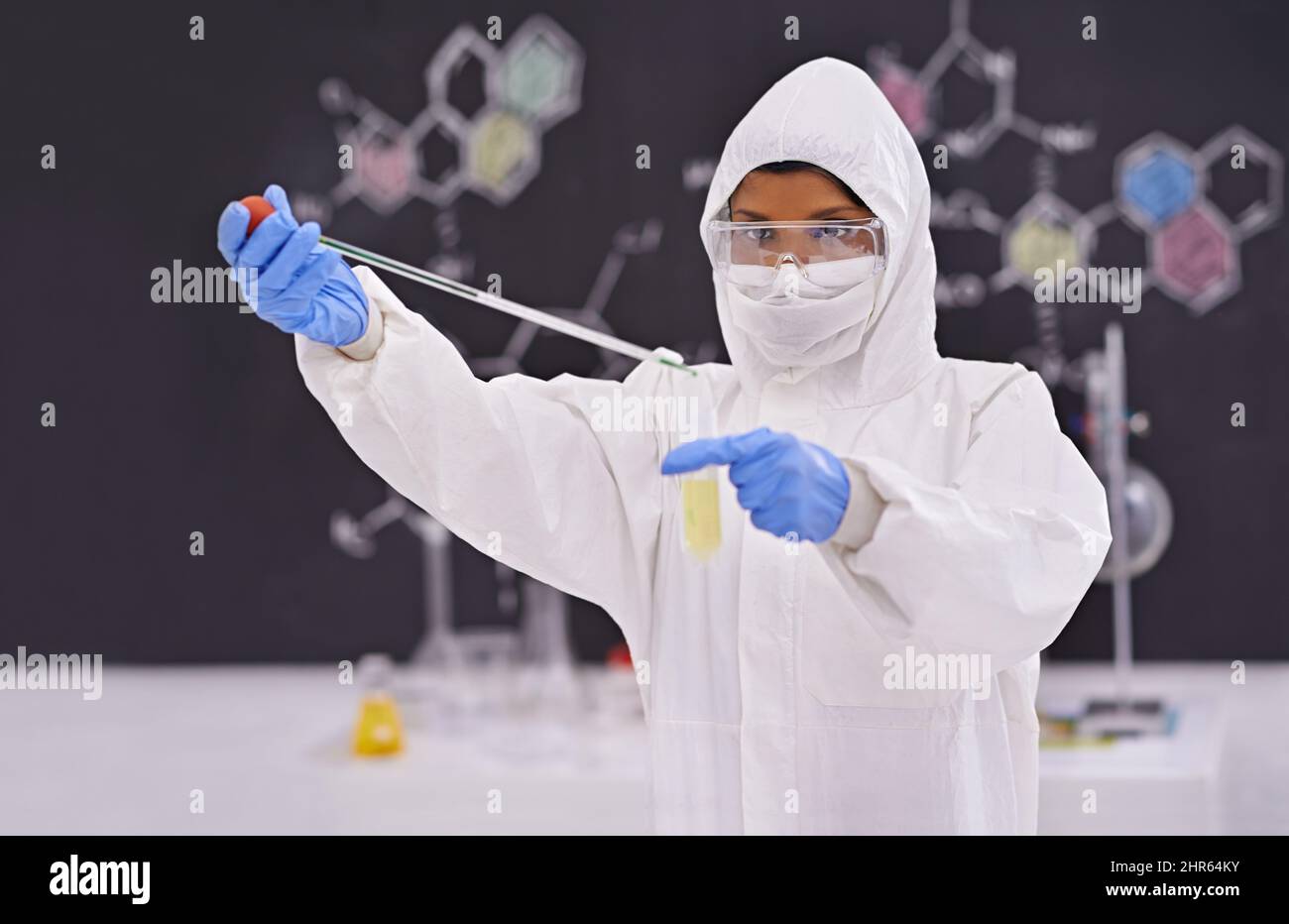 Caution in the lab. A young scientist in protective clothing using a