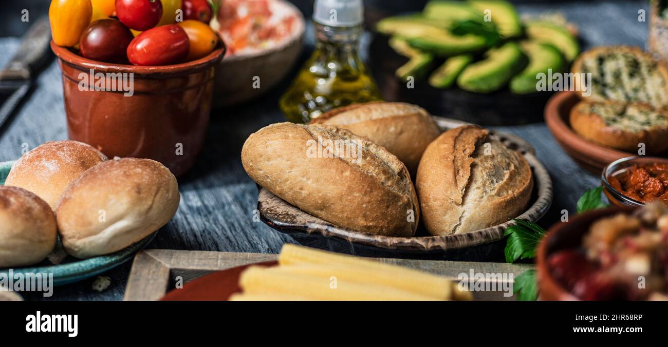 closeup of a table with some different ingredients to prepare vegan sandwiches, such as bread buns, baby corns, cherry tomatoes or avocado, in a panor Stock Photo