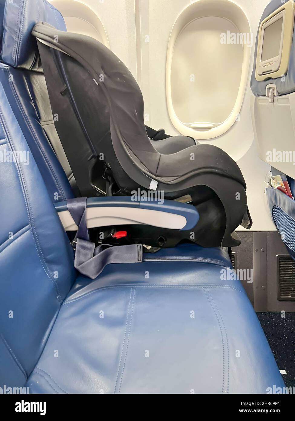 Child car seat placed next to a window on an airplane Stock Photo - Alamy
