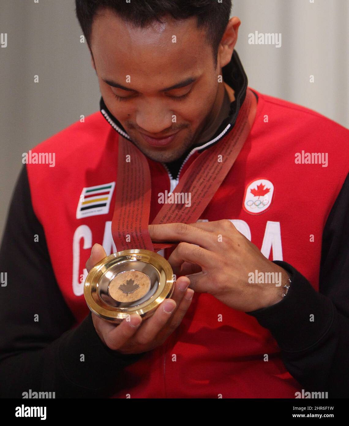 CORRETED VERSION - CORRECTS SPELLING OF NAME - Gilmore Junio reads the names of donors on the strap of his medal, at King Edward School, after he was presented with a commemorative crowdsourced Medal of Thanks in Kitchener, Ont., Wednesday, May 14, 2014. The medal, made of Canadian Maple wood, silver and gold, was conceived by the Toronto design firm Jacknife to thank Junio for his selfless act of stepping aside for teammate Denny Morrison to skate in the 1,000 metre speed skating race at the Sochi Olypics. THE CANADIAN PRESS/Dave Chidley Stock Photo