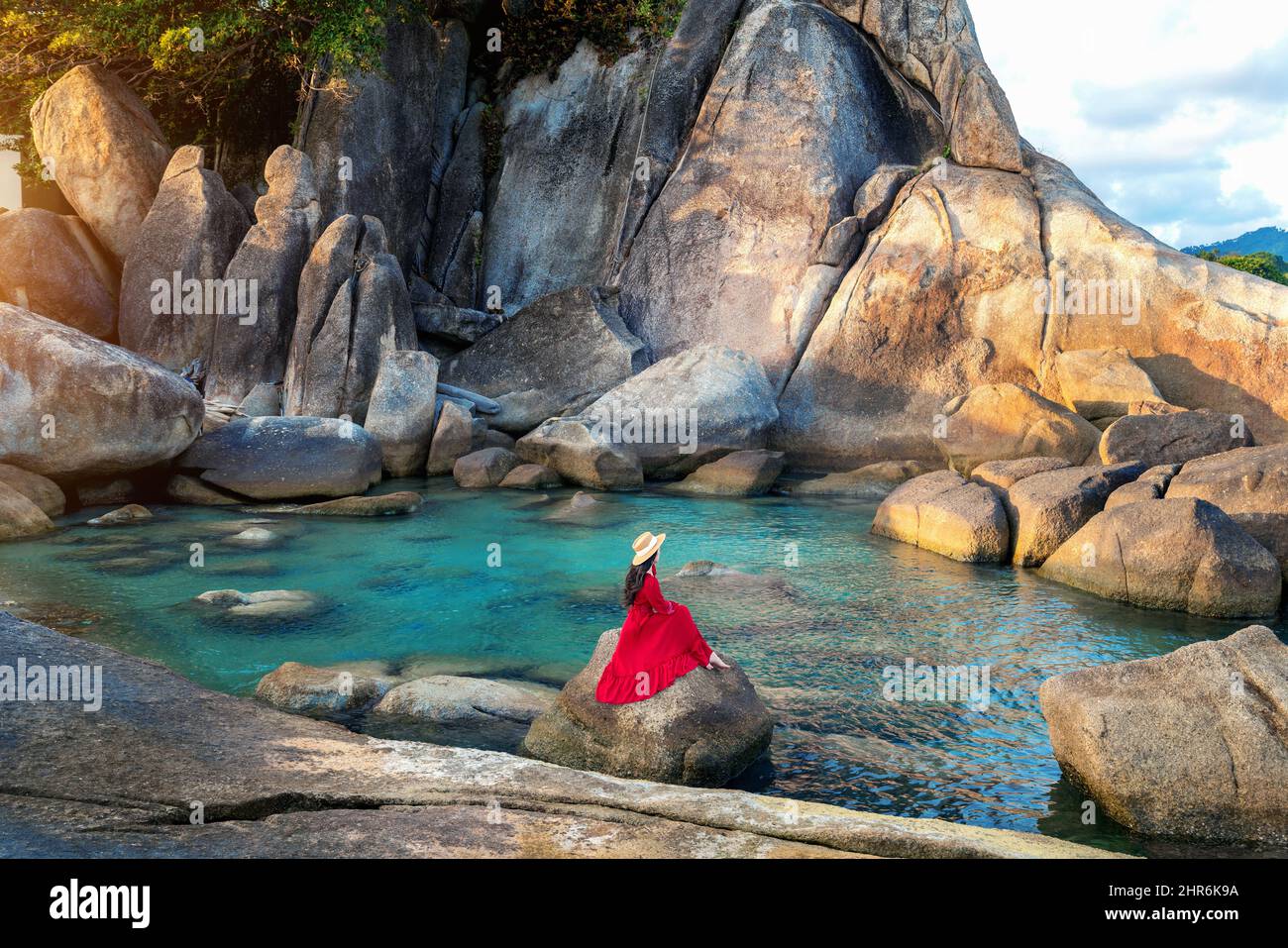 Tourist sitting on the rock near Grandfather and grandfather rock (Hin Ta and Hin Yai Rocks) on the Lamai Beach, Koh Samui, Thailand. Stock Photo