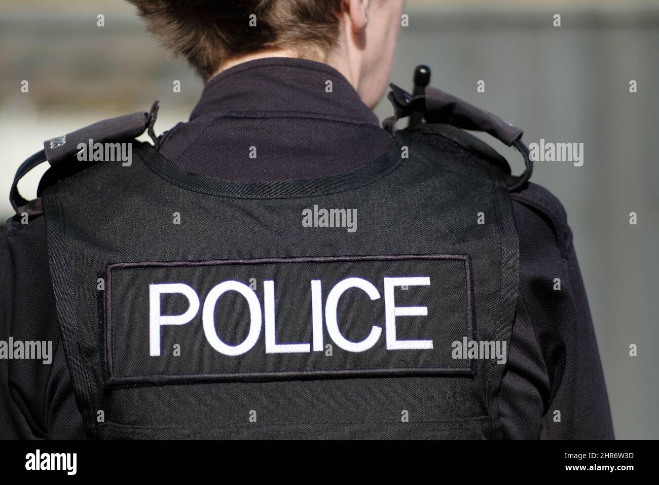 A rear view of a British female police officer in full uniform and wearing body armour. The image clearly shows the officers police insignia Stock Photo