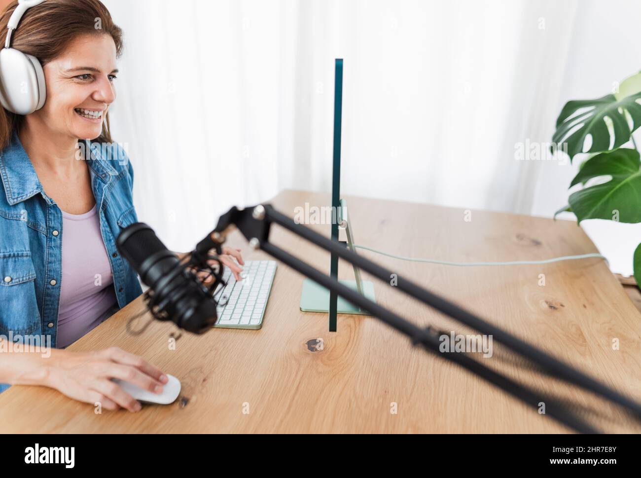 Happy woman recording a podcast using computer and microphone from her home studio Stock Photo