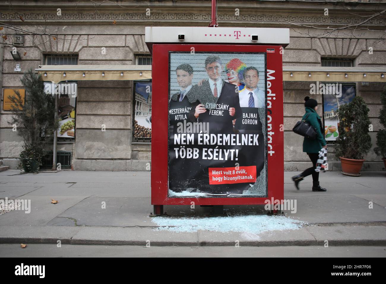 In Budapest a woman walks past the shattered glass of an anti-opposition poster before elections. Ferenc Gyurcsány is in the middle. Stock Photo
