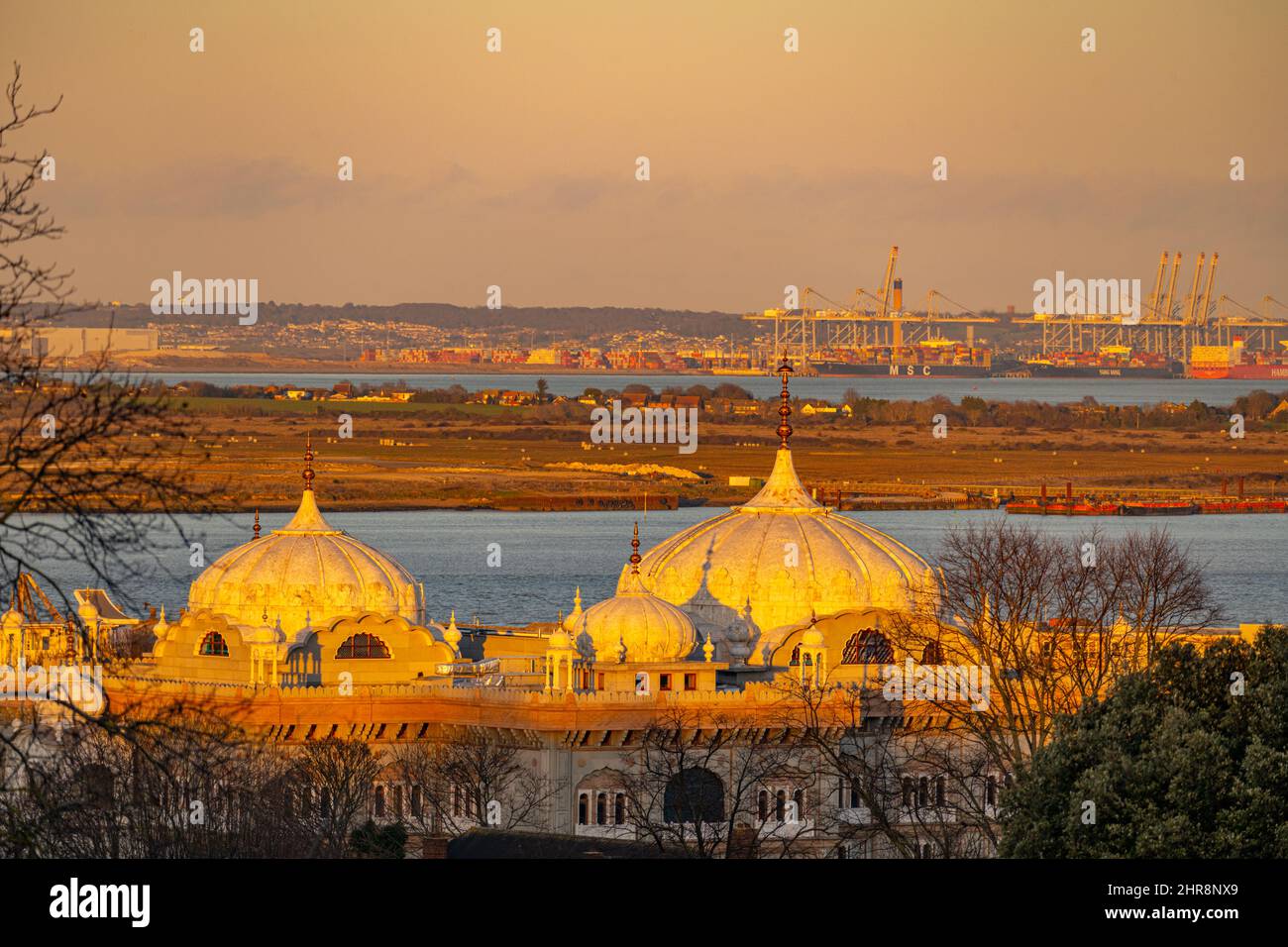 Looking towards Thames Gateway port with the domes of the  Guru Nanak Darbar Gurdwara in Gravesend in foreground at sunset Stock Photo