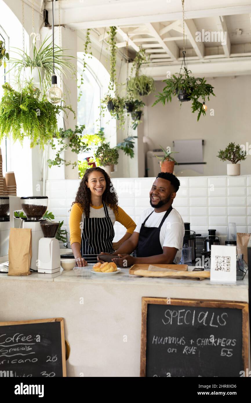 Portrait of happy african american barista coworkers standing at counter in cafe Stock Photo
