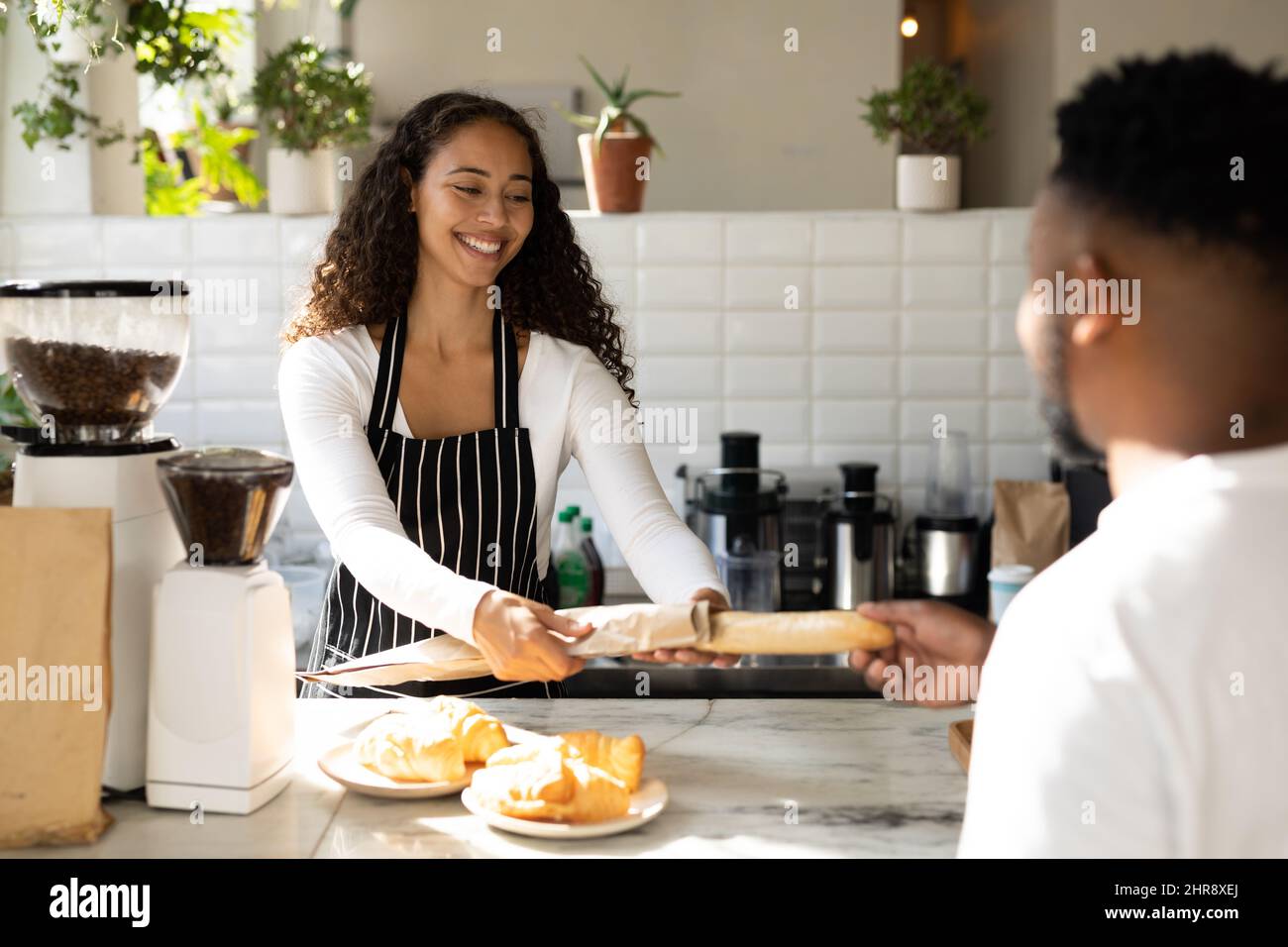 Smiling african american barista serving male customer at counter in