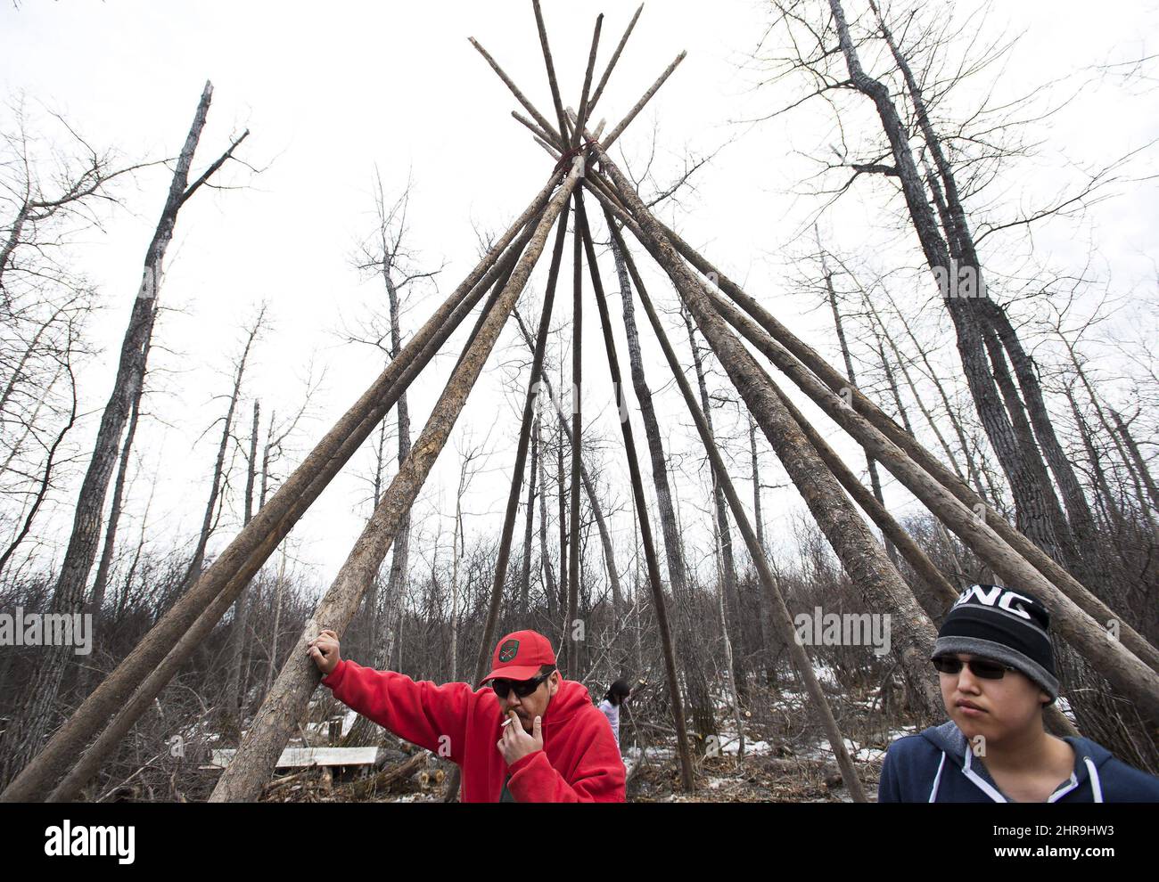 A Ranger and an indigenous boy wait to skin a caribou for dinner at a ...