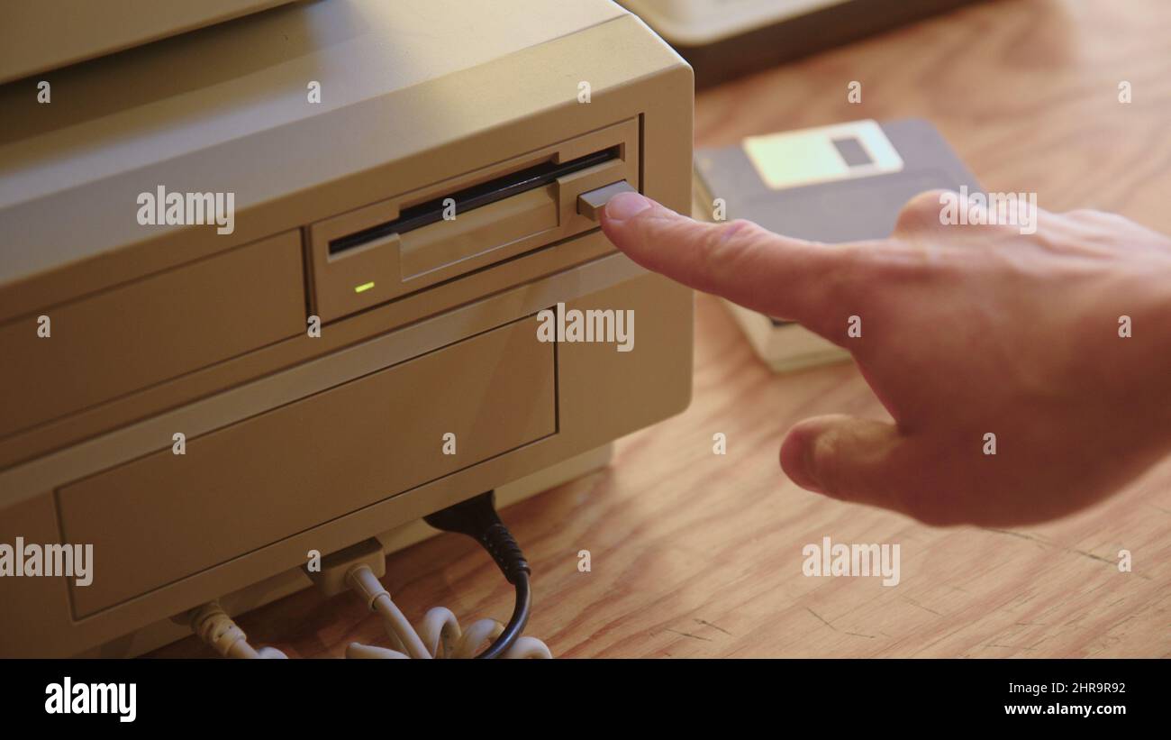 Hand inserting and ejecting Floppy Disk into vintage Commodore Amiga 2000 PC. Popular Gaming PC in the 80s and 90s. Stock Photo