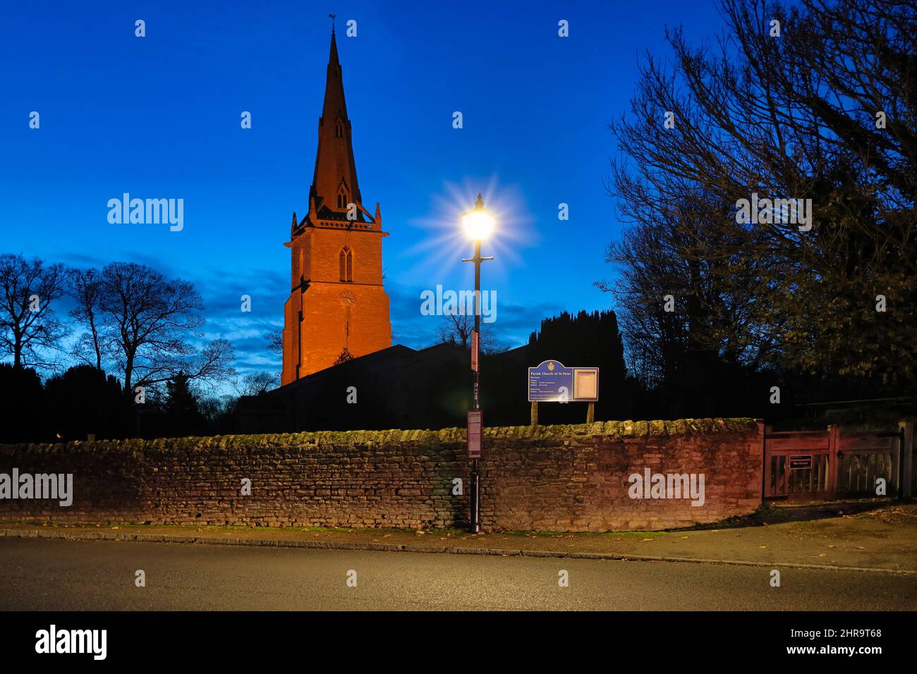 St Peter's Church, Sharnbrook, Bedfordshire, UK - Street lamp and parish church tower lit up at night Stock Photo