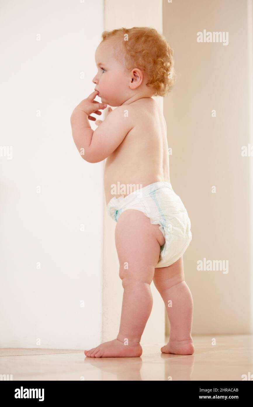 Starting to explore his world. Adorable baby boy standing by himself and looking away. Stock Photo