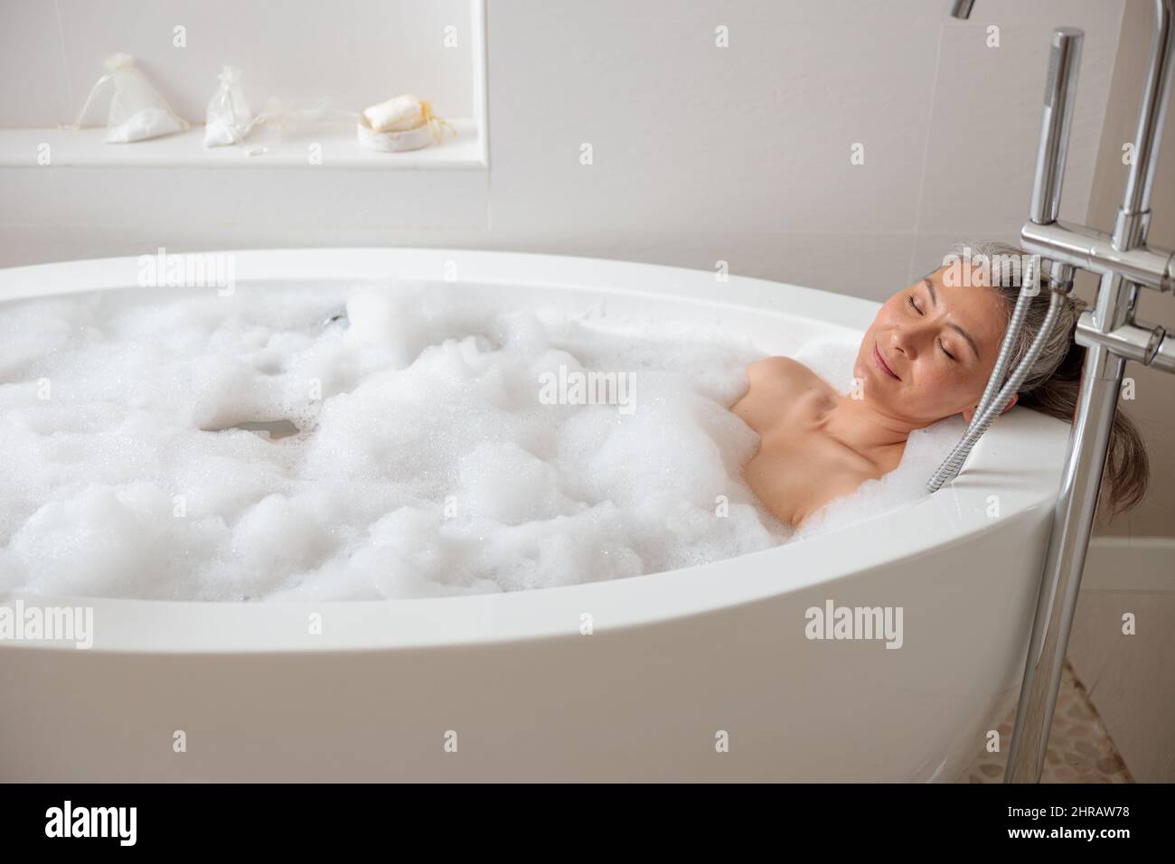 Beautiful adult lady lying in the bathtube Stock Photo
