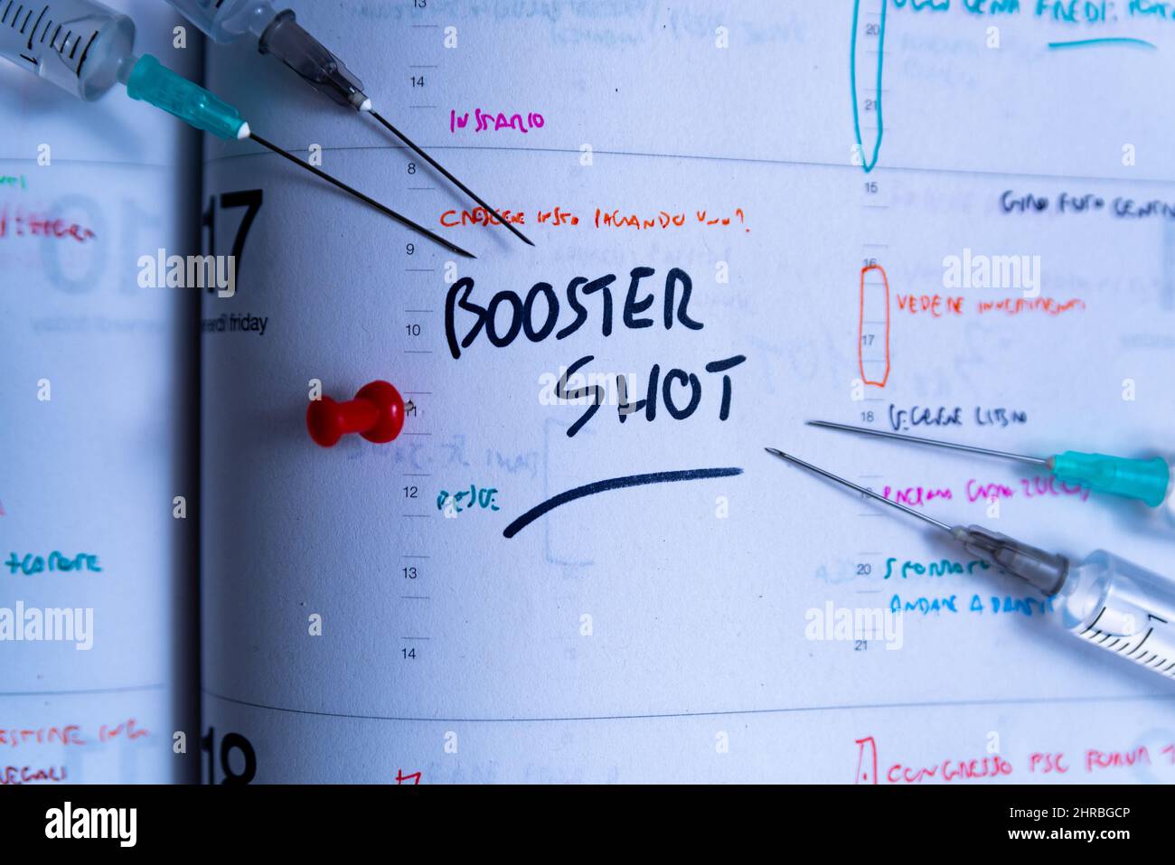Booster shot Covid vaccination campaign and jab concept on agenda. Syringe on calendar with as a concept for the fourth covid-19 vaccine dose to fight Stock Photo