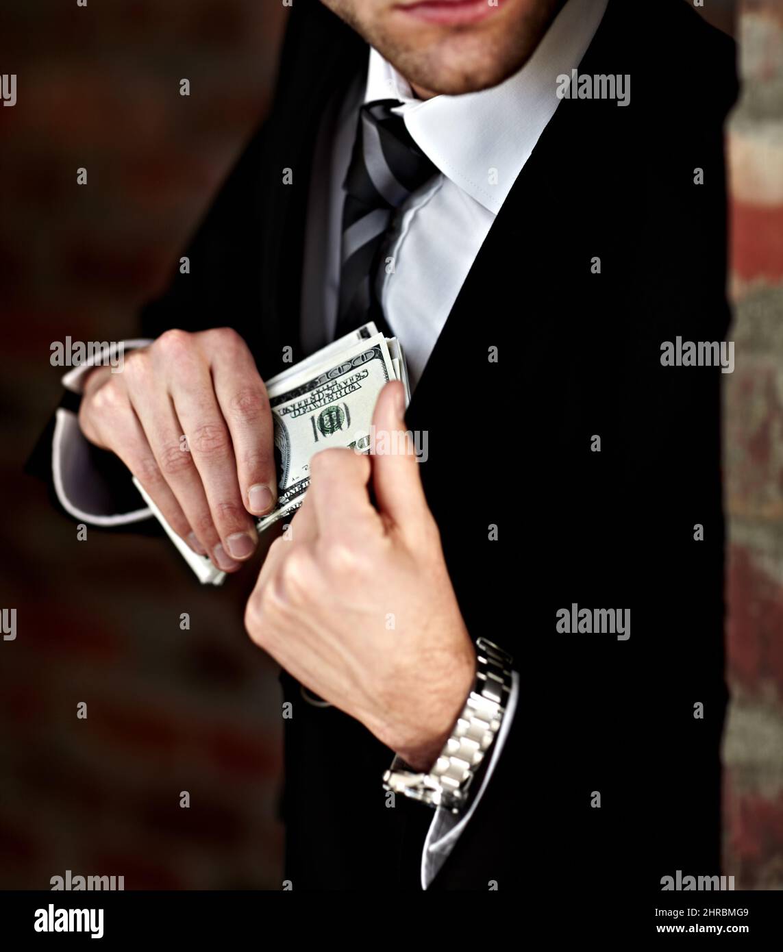 Hes got his payoff. Cropped shot of a man tucking a wad of cash into his jacket. Stock Photo