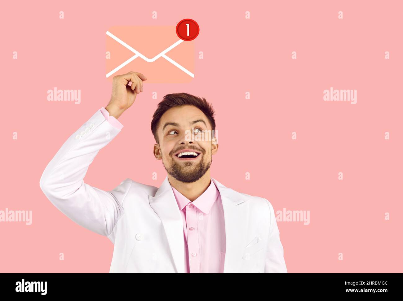 Happy young man holding pink envelope with red notification about new message in inbox Stock Photo