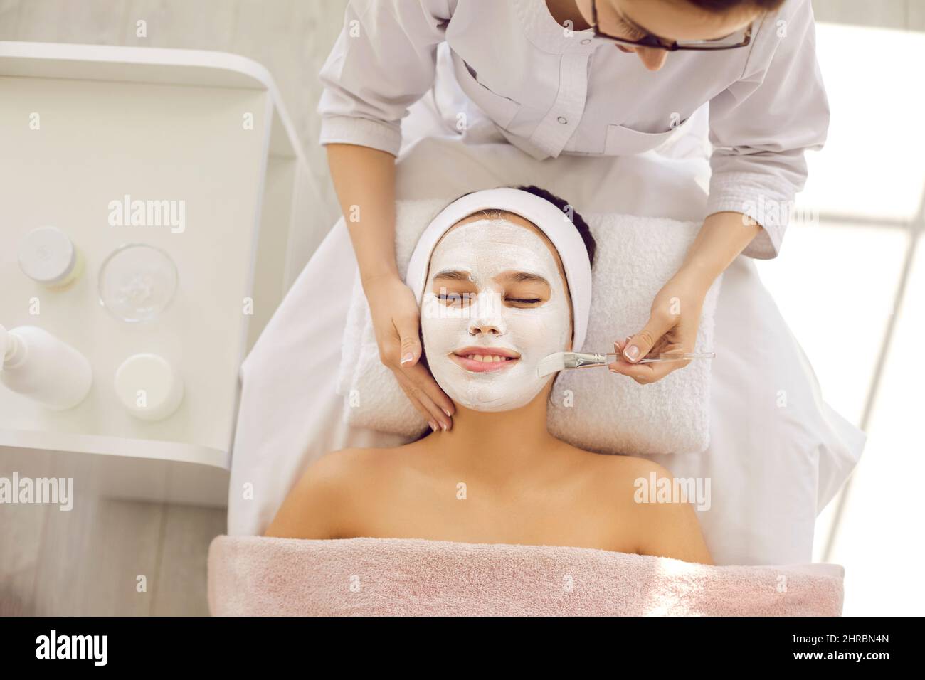 Portrait of satisfied smiling female client enjoying skin care procedure in spa salon. Stock Photo