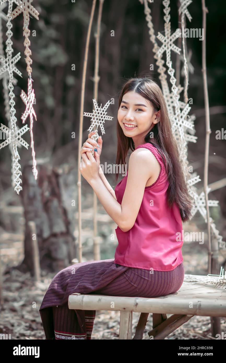 Portrait of a smiling woman sitting on a bench in a rural village, Thailand Stock Photo