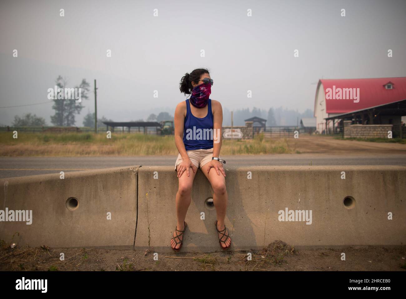 canadian girls ash Luana Avila wears a bandana over her face because of smoke and ash in the  air from wildfires as she waits for her children at gas station in Little  Fort, B.C., on