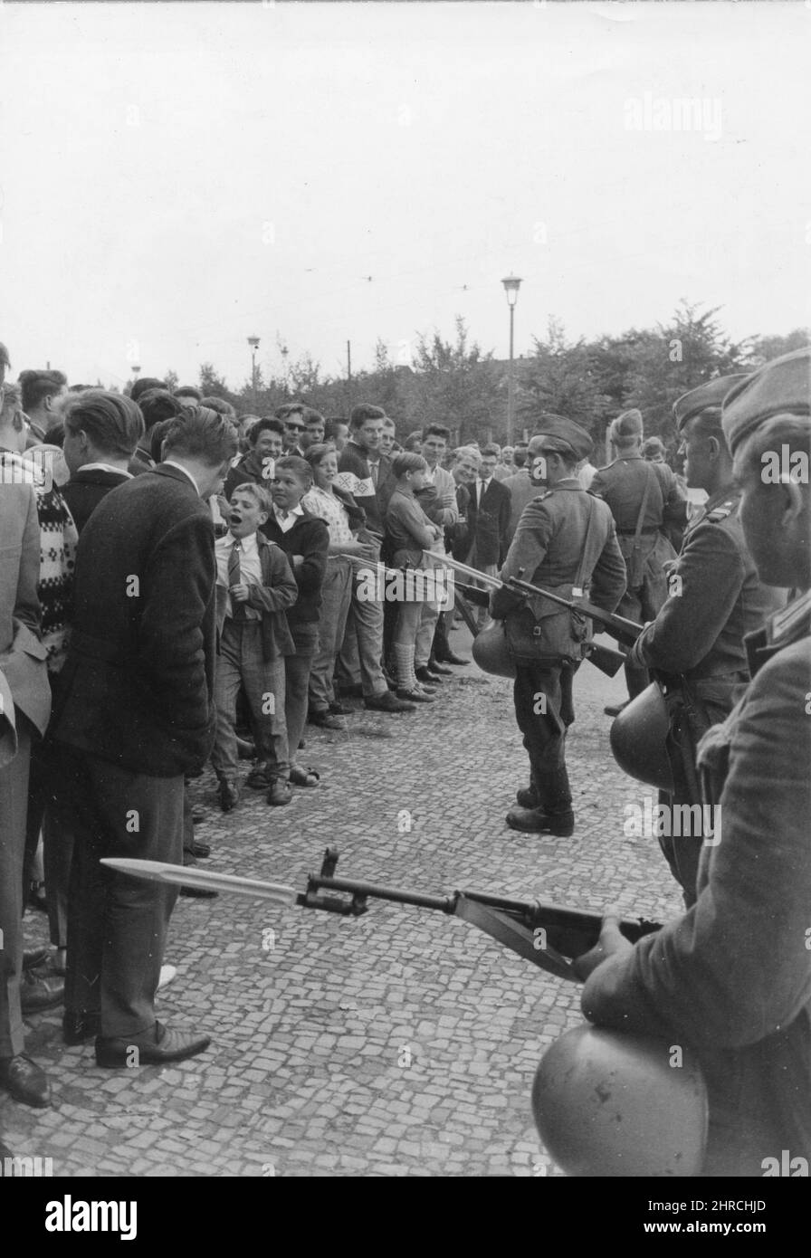 Heavily armed troops of the East German police patrol along the Red sector of the city to halt the flow of East Germans into the West. Here they use bayonets to push back the crowds. The cold steel and heavy military activity reduced the flow of refugees to a trickle. Berlin, Germany, 1961. Stock Photo