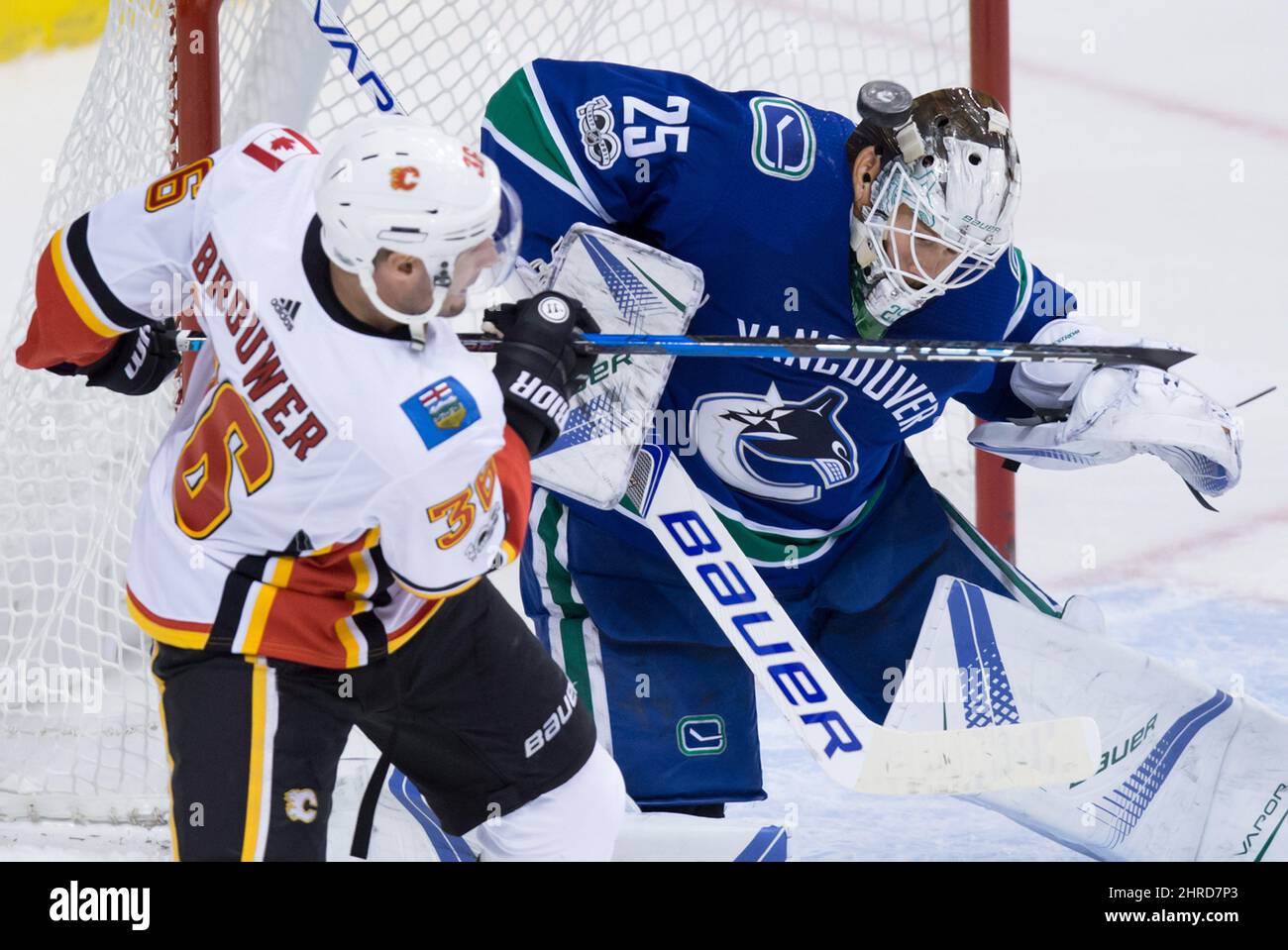A shot deflects off the mask of Vancouver Canucks goalie Jacob Markstrom,  right, of Sweden, as Calgary Flames' Troy Brouwer tries to get his stick on  the puck during the second period