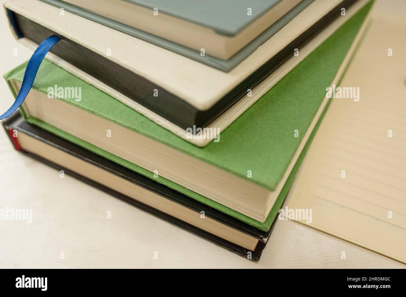 Closeup of a stack of colorful books next to a piece of paper on a ...