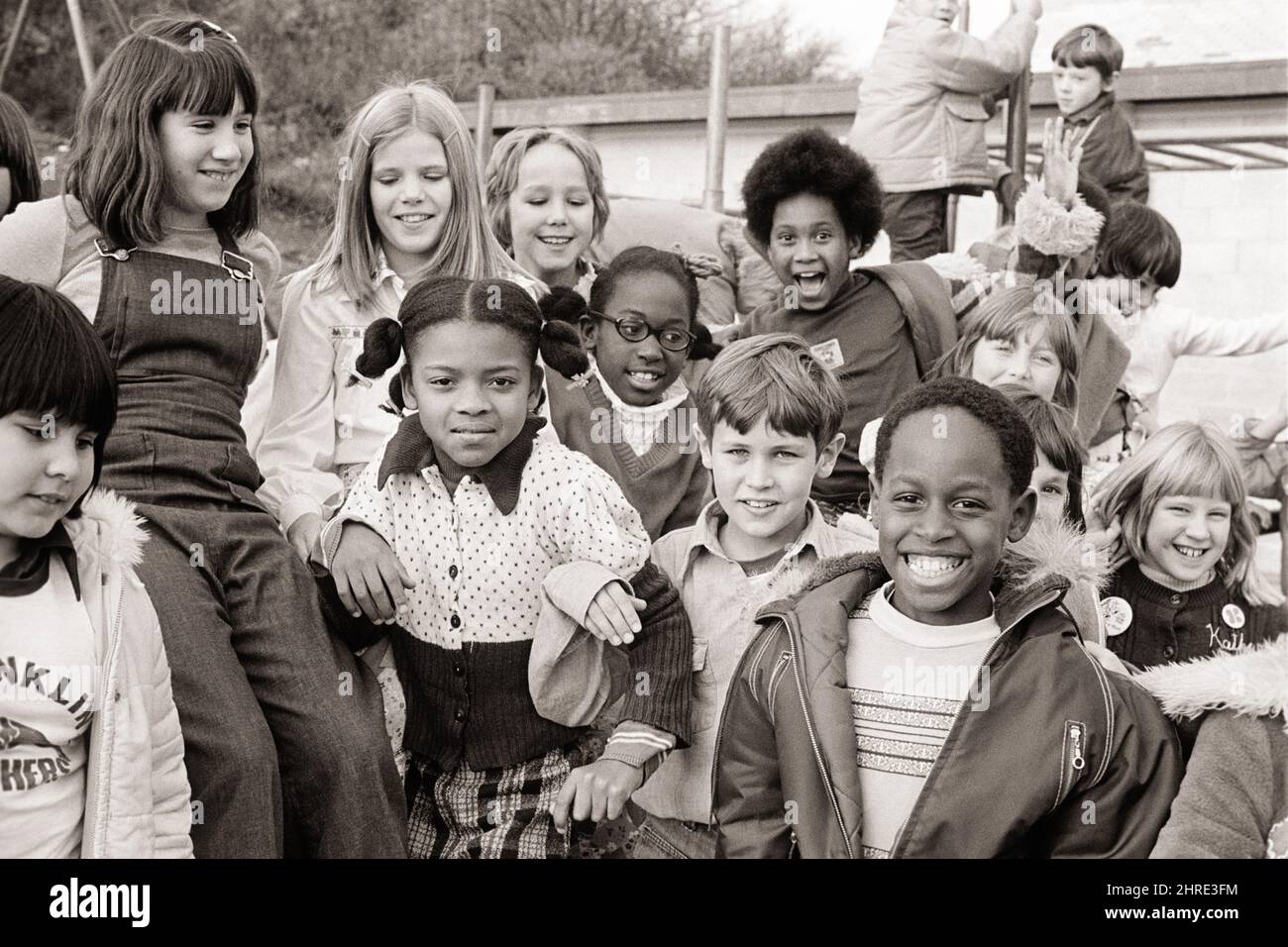 1970s GROUP OF DIVERSE SCHOOL CHILDREN OUT FOR RECESS IN PLAYGROUND POSING FOR A GROUP PORTRAIT SMILING  - j14363 HAR001 HARS LAUGH SPANISH DIFFERENT PLEASED JOY LIFESTYLE SATISFACTION FEMALES COPY SPACE FRIENDSHIP HALF-LENGTH PERSONS MALES CONFIDENCE B&W EYE CONTACT SCHOOLS GRADE HAPPINESS CHEERFUL ORIENTAL AFRICAN-AMERICANS AFRICAN-AMERICAN EXCITEMENT RECESS RECREATION BLACK ETHNICITY ASIAN AMERICAN POSING PRIMARY SMILES JOYFUL VARIOUS VARIED ASIAN-AMERICAN GRADE SCHOOL GROWTH PRE-TEEN PRE-TEEN BOY PRE-TEEN GIRL TOGETHERNESS BLACK AND WHITE CAUCASIAN ETHNICITY HAR001 HISPANIC ETHNICITY Stock Photo