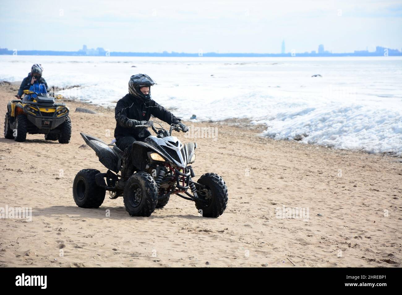 ZELENOGORSK, RUSSIA- APRIL 09, 2017: Two men ride quadcopters across the sand along the frozen Gulf of Finland. Russia, St. Petersburg, spring Stock Photo