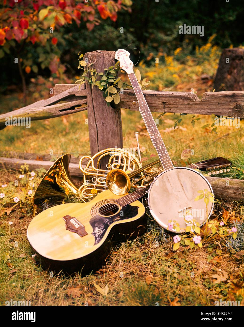 1970s ARRANGEMENT OF MUSICAL INSTRUMENTS GUITAR BANJO FRENCH HORN AND TROMBONE LEANING AGAINST WOODEN SPLIT RAIL FENCE OUTDOORS - km5840 PHT001 HARS CONCEPT CONCEPTUAL STILL LIFE ARRANGEMENT STYLISH TROMBONE STRINGED SYMBOLIC CONCEPTS CREATIVITY ROOTS TOGETHERNESS FRENCH HORN OLD FASHIONED REPRESENTATION Stock Photo