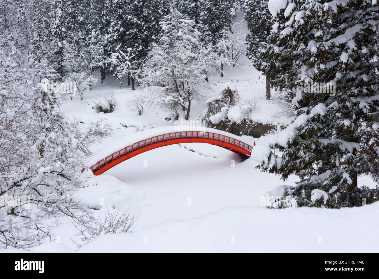 A red bridge buried in snow in the forest, Yokote, Akita Prefecture, Japan Stock Photo