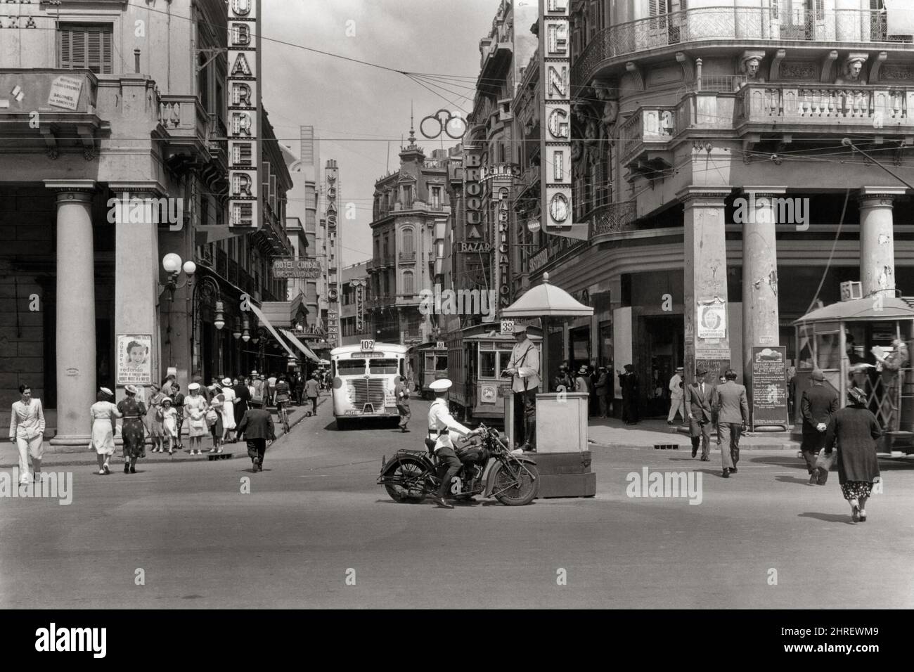 1930s 1940s DOWNTOWN INTERSECTION PEDESTRIANS TROLLEY AND BUS TRAFFIC TWO POLICE AT PLAZA INDEPENDENCIA IN MONTEVIDEO URUGUAY - r12410 PAL001 HARS SKYLINE SERVE VEHICLE SAFETY LIFESTYLE HISTORY FEMALES JOBS COPY SPACE FULL-LENGTH LADIES PERSONS AUTOMOBILE MALES ORDER OFFICER TRANSPORTATION B&W COP DOWNTOWN SOUTH AMERICA SKILL OCCUPATION PROTECT SKILLS INTERSECTION PROTECTION AND AUTOS PROGRESS DIRECTION PRIDE AUTHORITY OCCUPATIONS TROLLEY UNIFORMS CONCEPTUAL AUTOMOBILES STYLISH VEHICLES PLAZA OFFICERS POLICEMEN COPS BADGE BADGES BLACK AND WHITE OLD FASHIONED Stock Photo