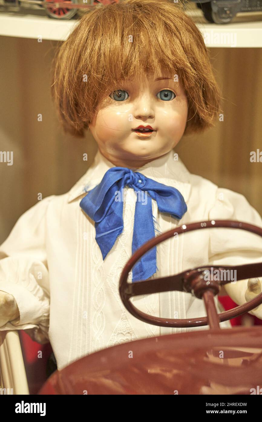 Closeup of a vintage toy boy doll sitting in a vehicle in the toy