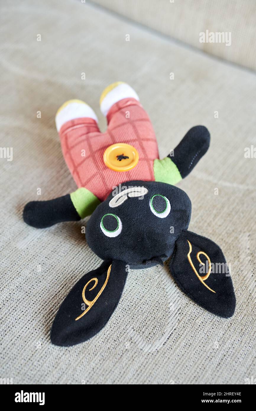 Vertical shot of a black Soft Bing the rabbit plush laying on a sofa ...