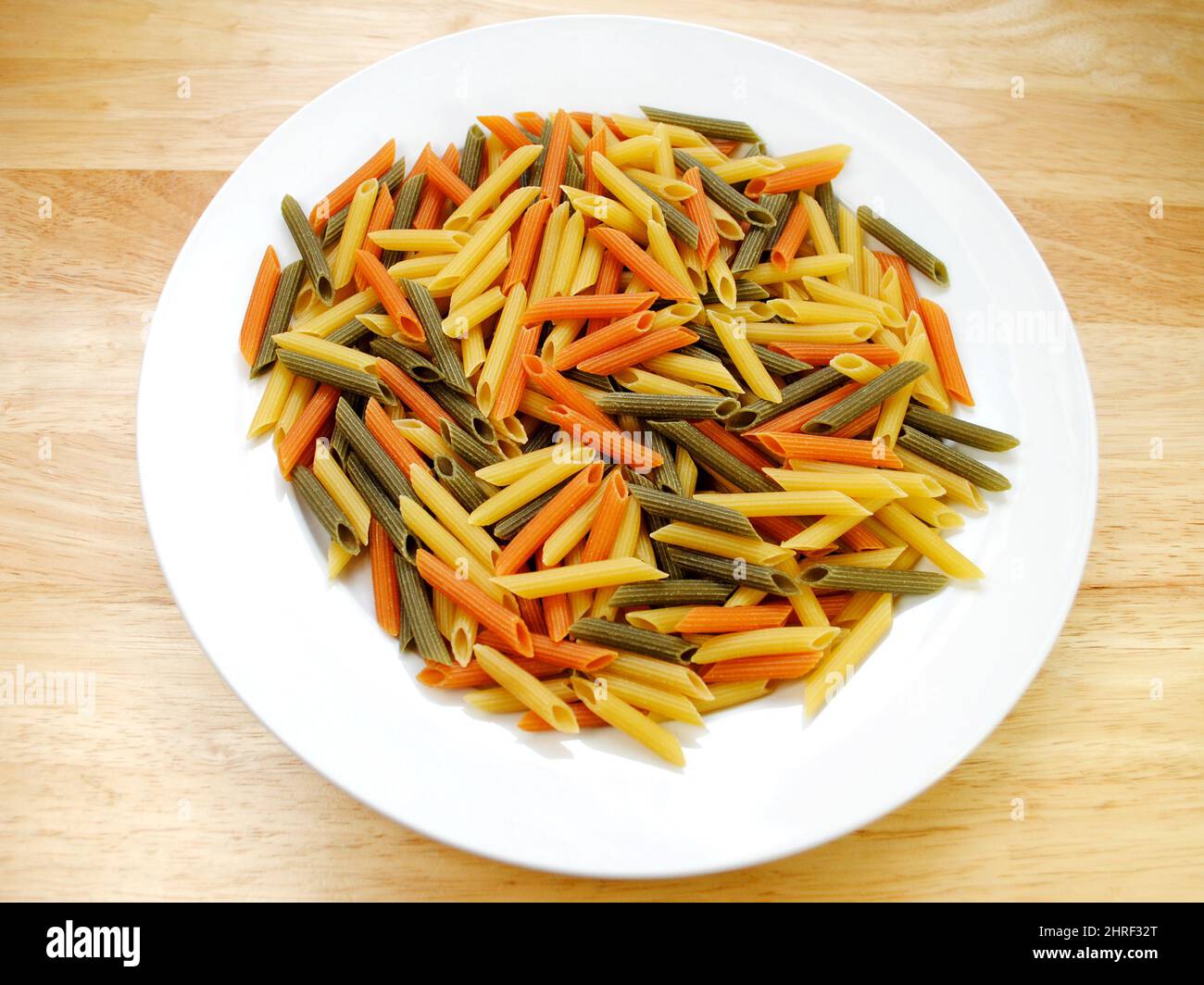 Bowl of Dry Cylinder-shaped Penne Pasta Noodles in Three Colors Yellow, Green and Red Stock Photo