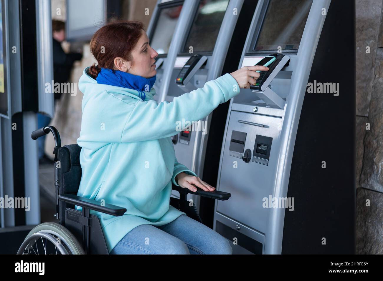 Caucasian woman in a wheelchair buys a train ticket using a mobile