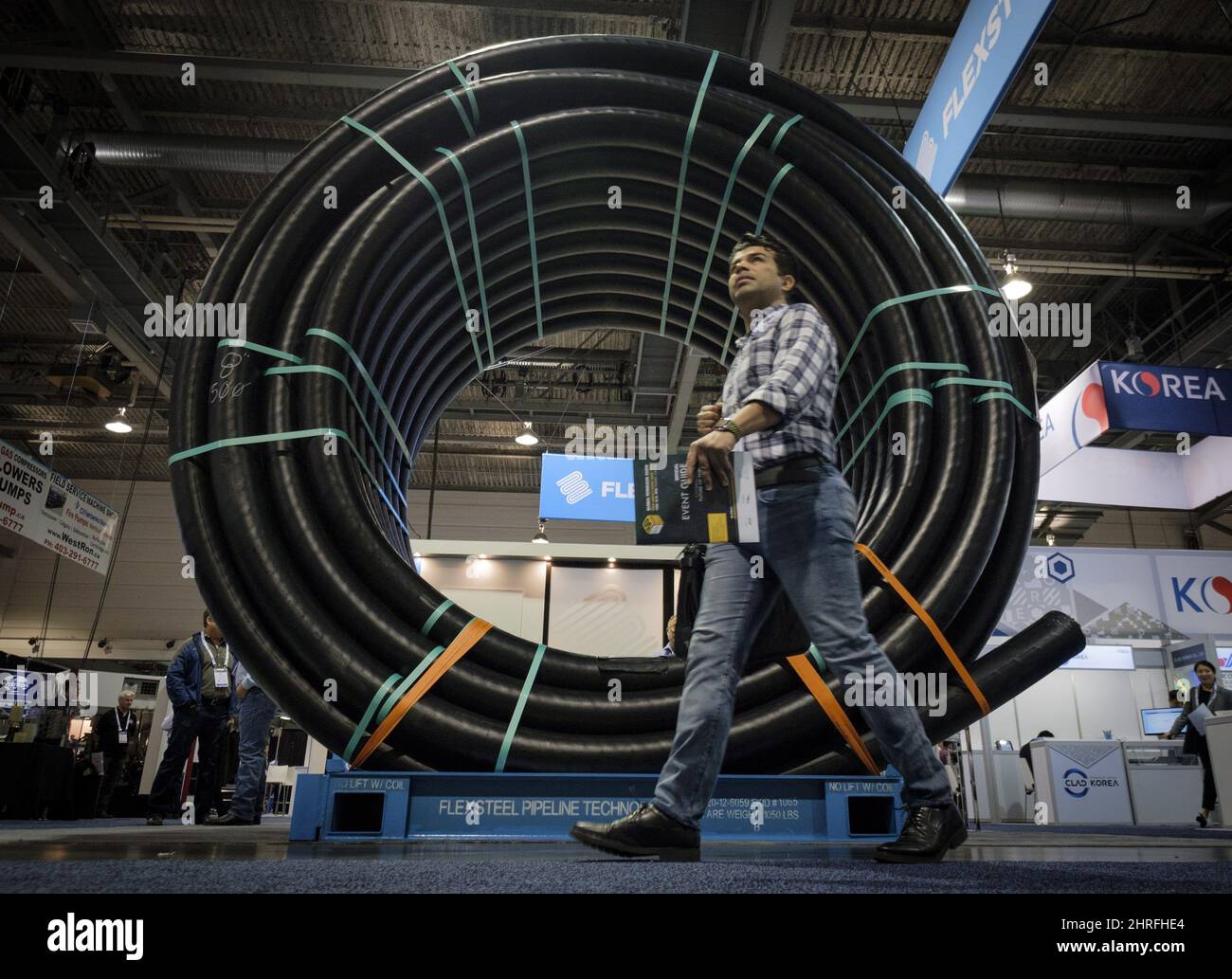 An attendee walks past a coil of flexible oil pipeline at the Global