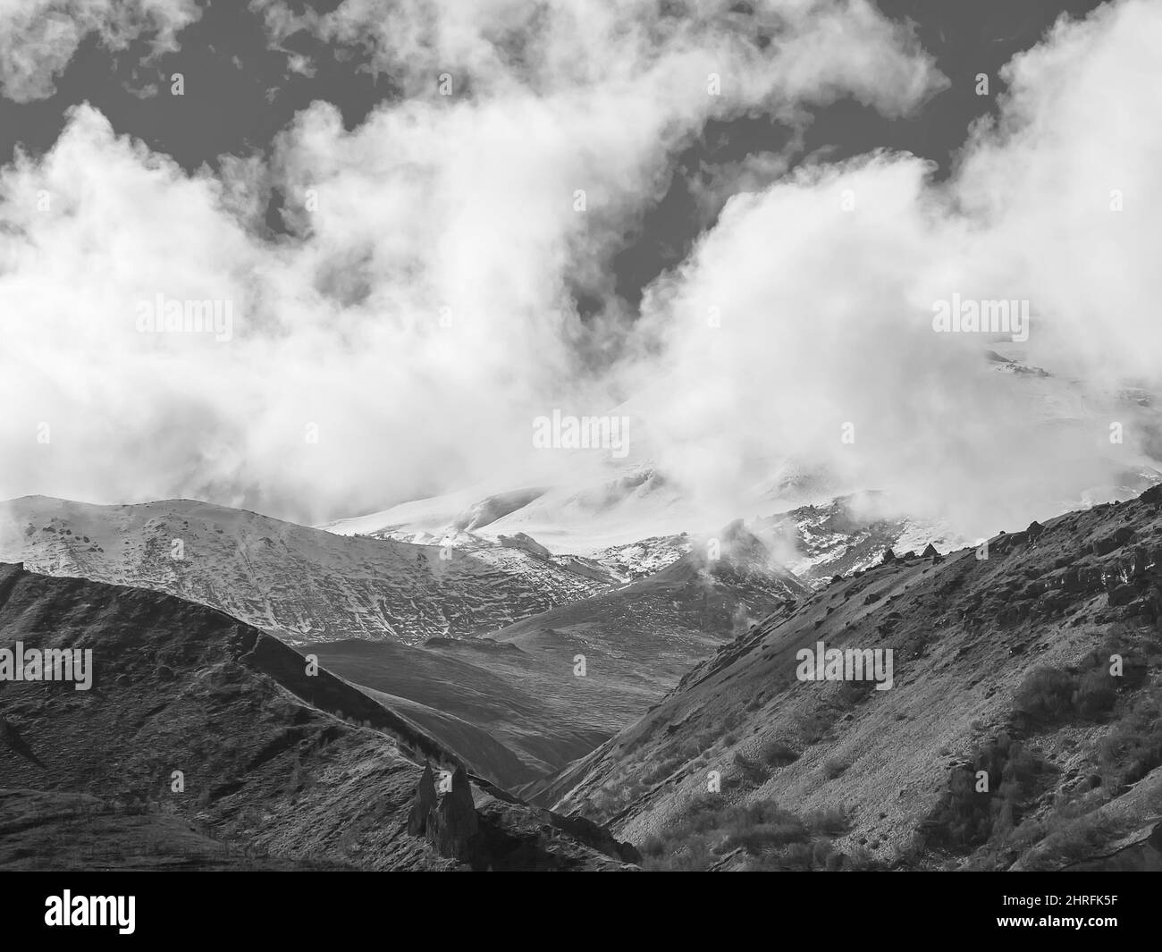 White clouds descended on majestic Elbrus in the Caucasian mountain valley. Black and white photo Stock Photo