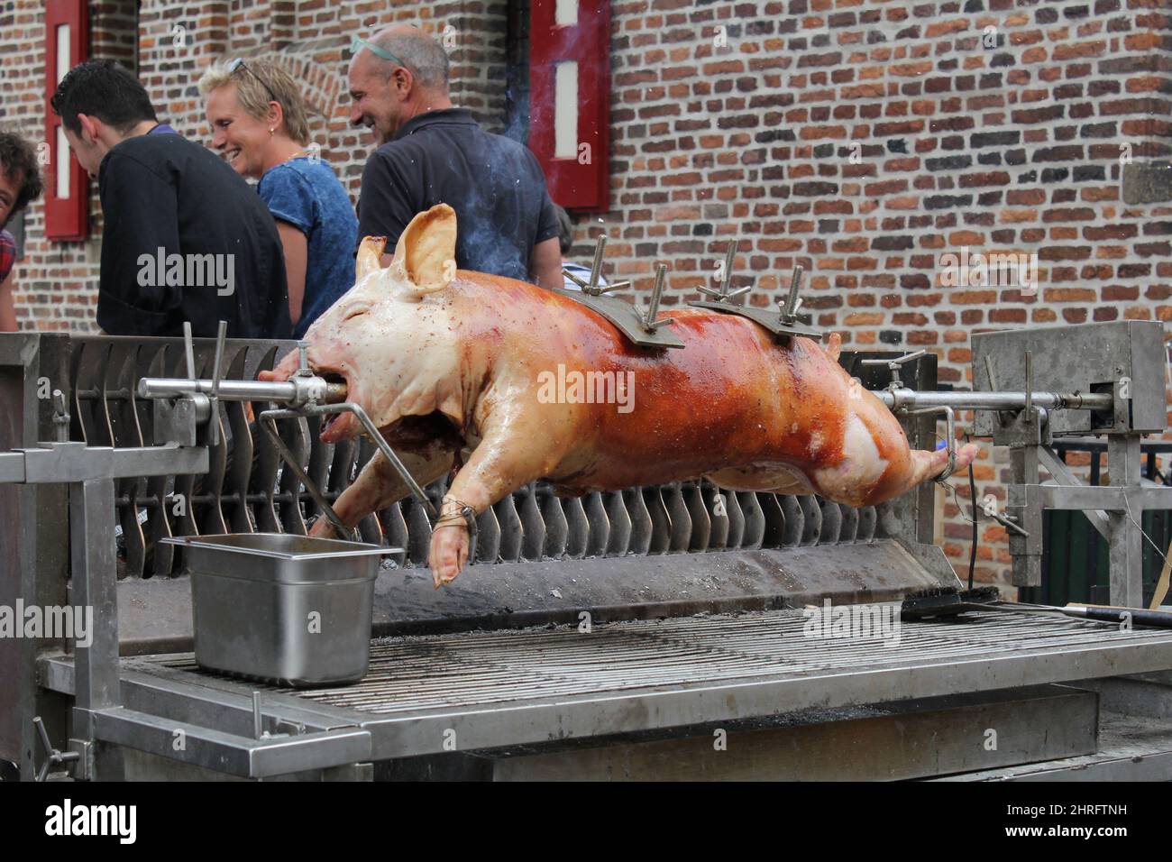 a pig is roasted at a spit at the medieval times festivities at an outdoor festival in summer Stock Photo