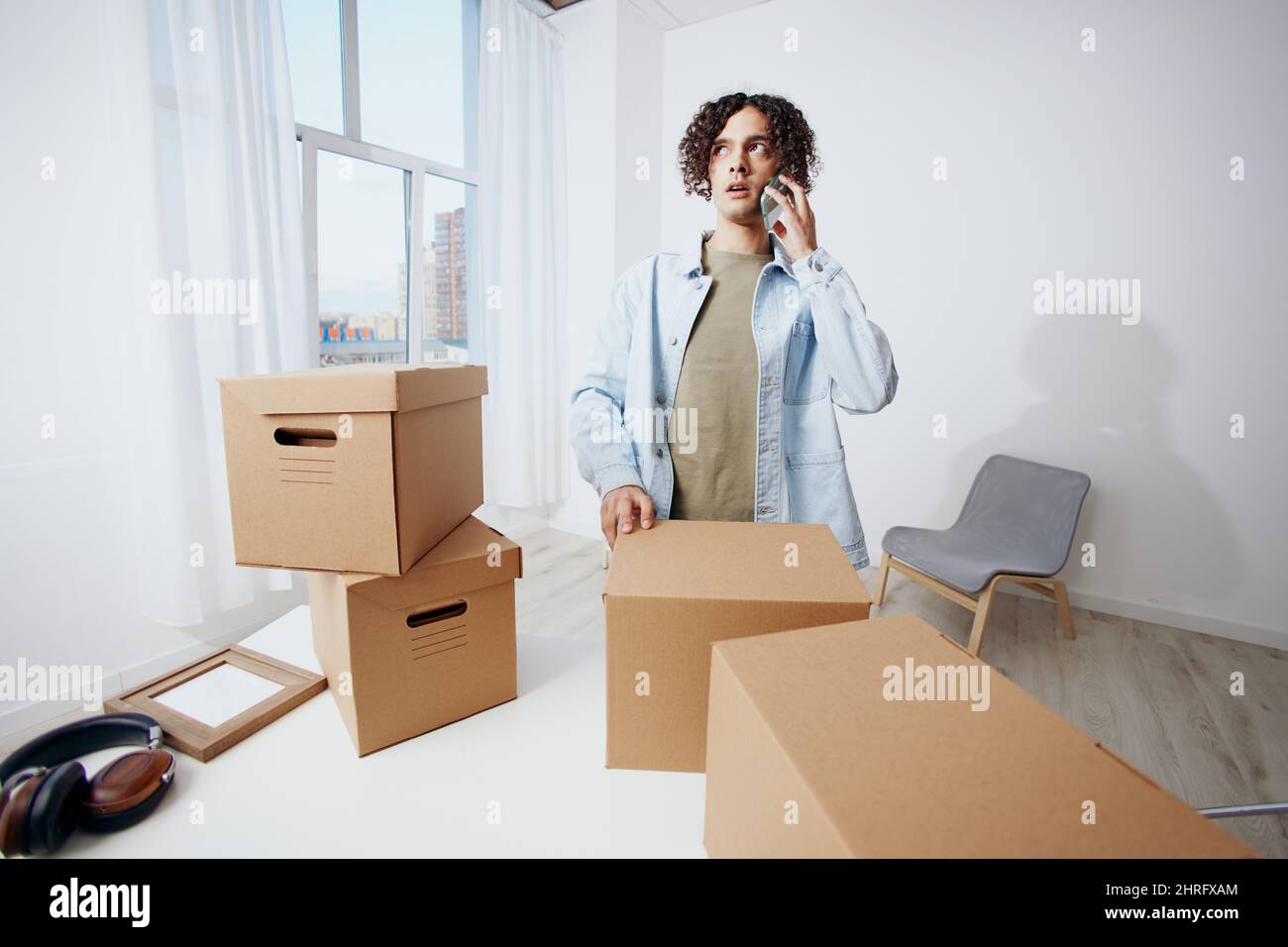 A young man unpacking things from boxes in the room sorting things out