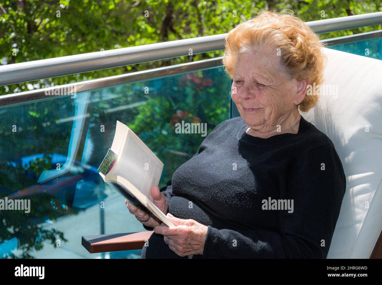 Caucasian woman reading a book in a garden on a sunny day Stock Photo ...