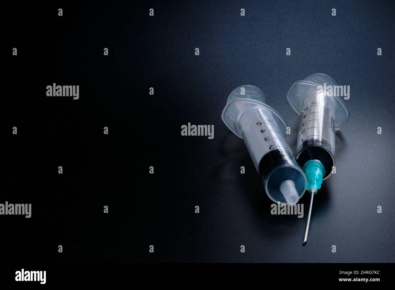 Small syringe with a hollow, sharppointed bevelcut needle on a black