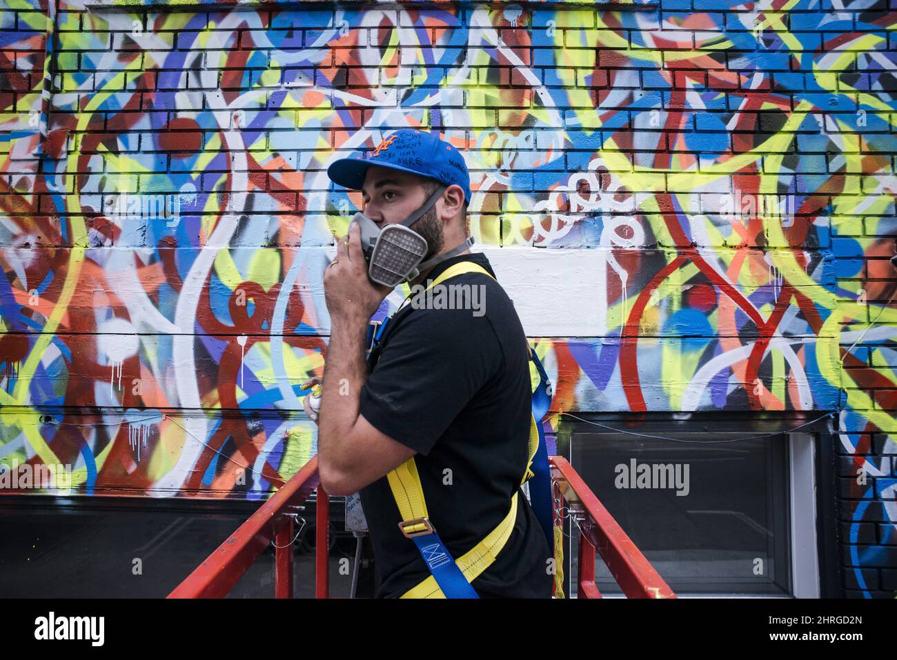 Anthony Ricciardi spray paints the eastern facade of a commercial