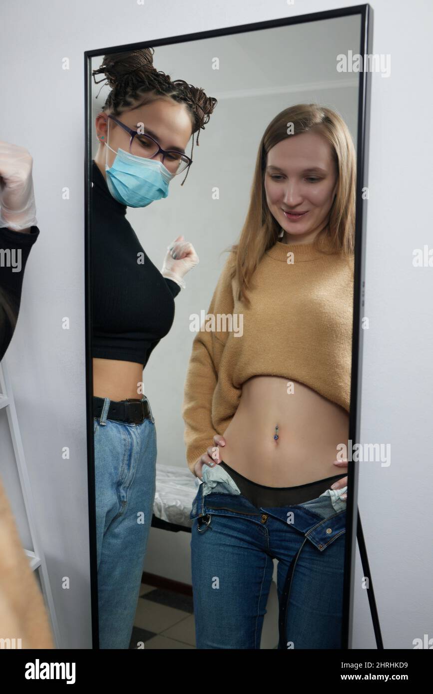 Close up of skin held in piercing tool as needle is ready to go in to pierce naval Stock Photo